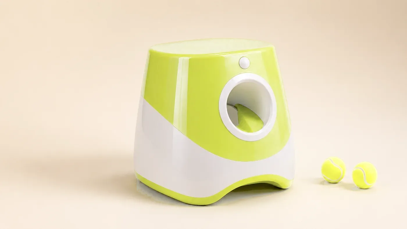The Pupserve automatic ball launcher seen three-quarters on a pale background, two balls beside it
