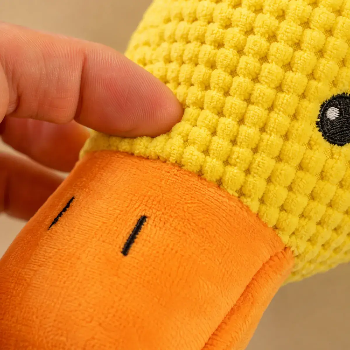 Close-up of the yellow waffle fabric and the orange beak, pinched between two fingers